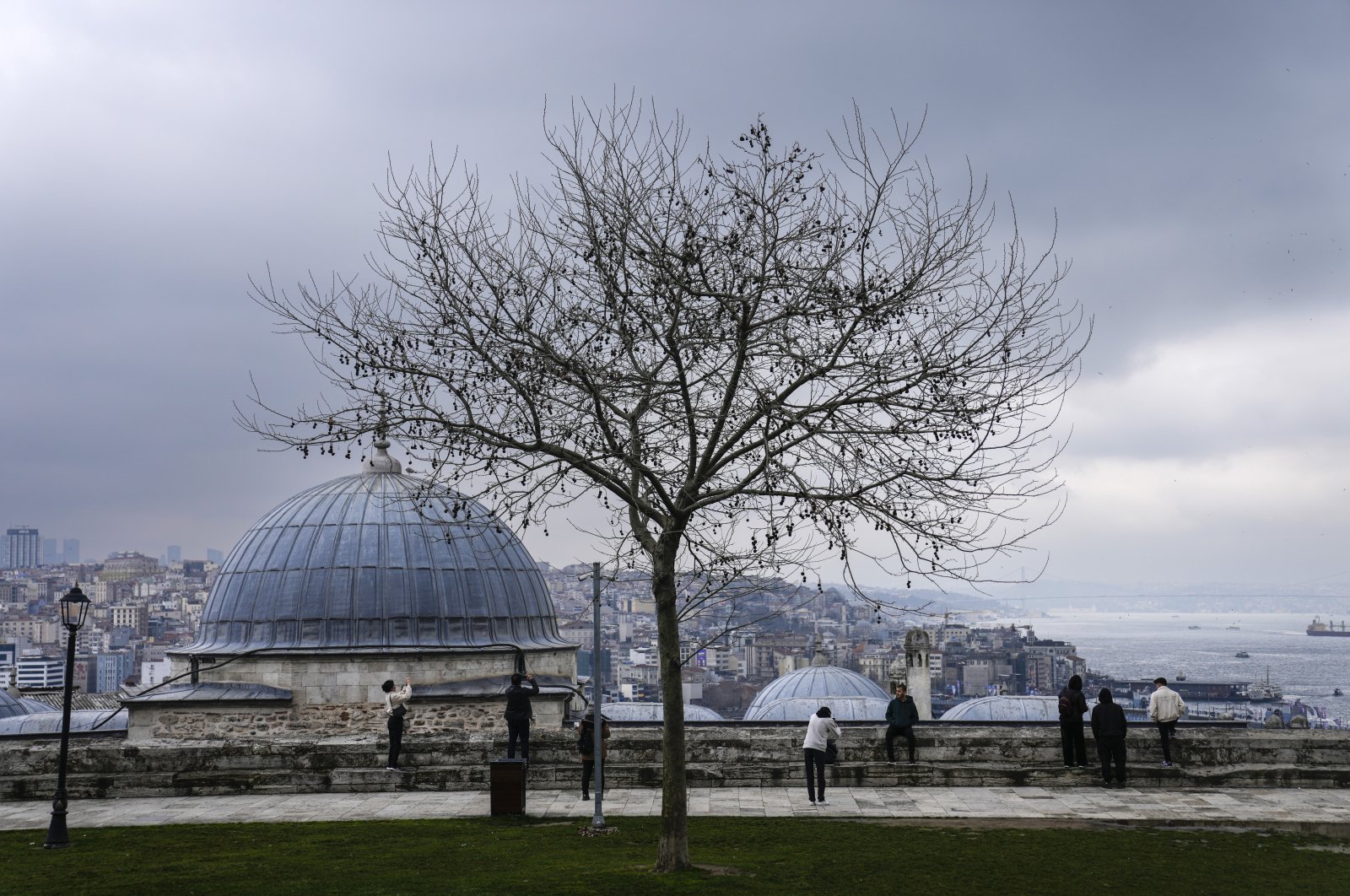 People look at the Bosporus from the Süleymaniye Mosque courtyard, Istanbul, Türkiye, March 15, 2024. (AP Photo)