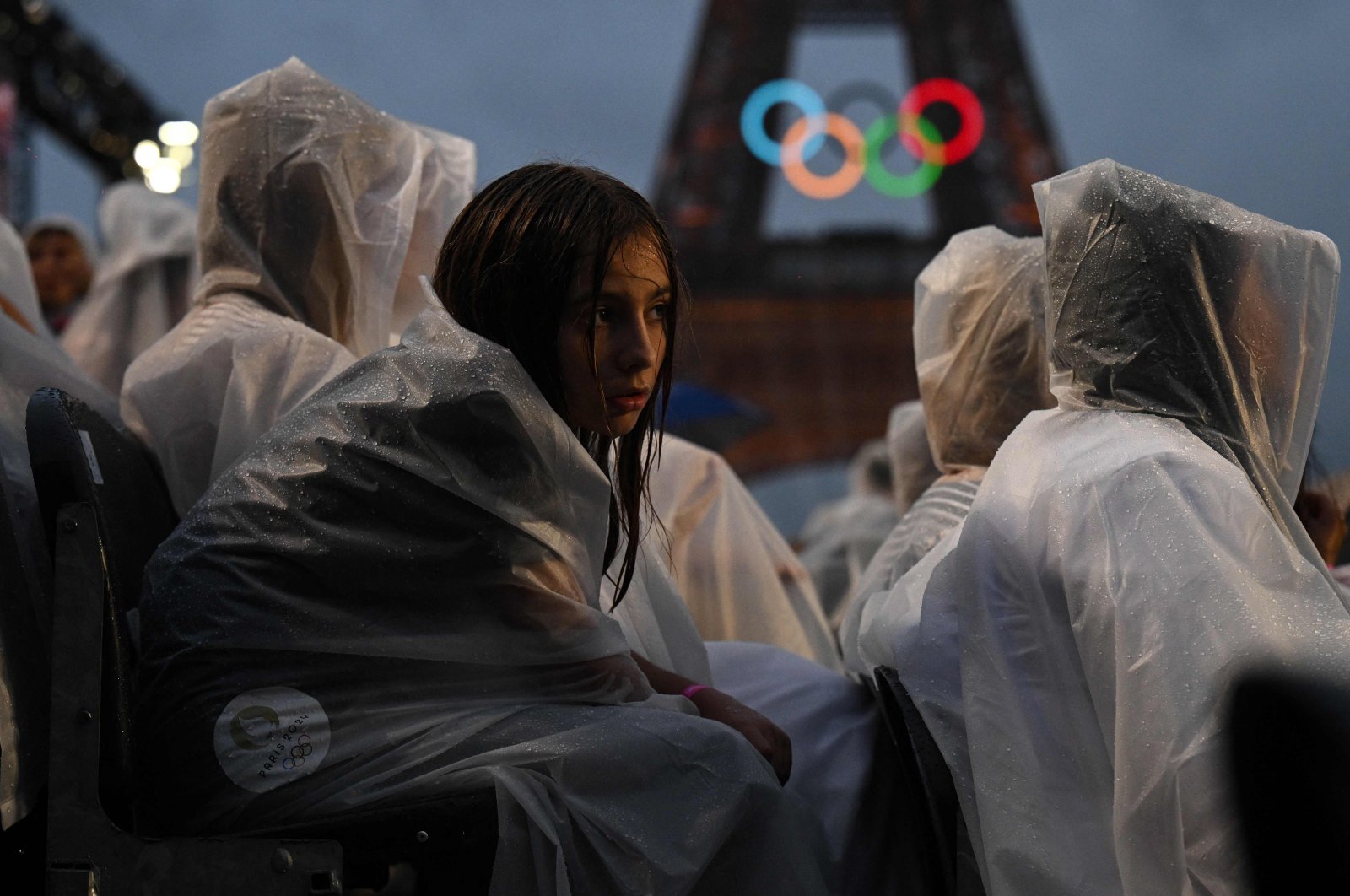 Attendees wear rain covers as they sit in the stands during the opening ceremony of the Paris 2024 Olympic Games as the Eiffel Tower is seen in the background, Paris, France, July 26, 2024. (AFP Photo)