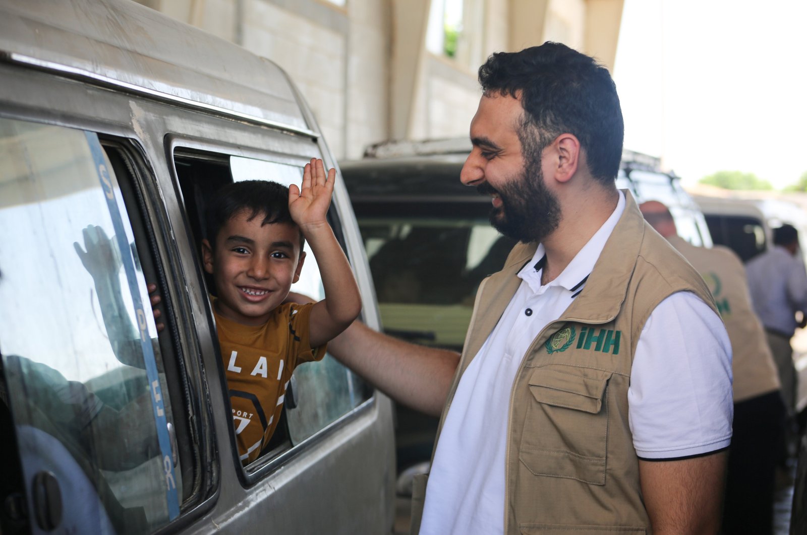 A Humanitarian Relief Foundation (IHH) official reacts to an Iraqi child waving as a group of displaced Iraqis crosses the Tal Abyad border gate to return home to Iraq, northern Syria, July 29, 2024. (AA Photo)