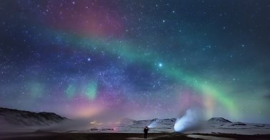 A person enjoys the northern lights over a geothermal hot spring area, Hverarond, Iceland, March 11, 2015. (Getty Images)
