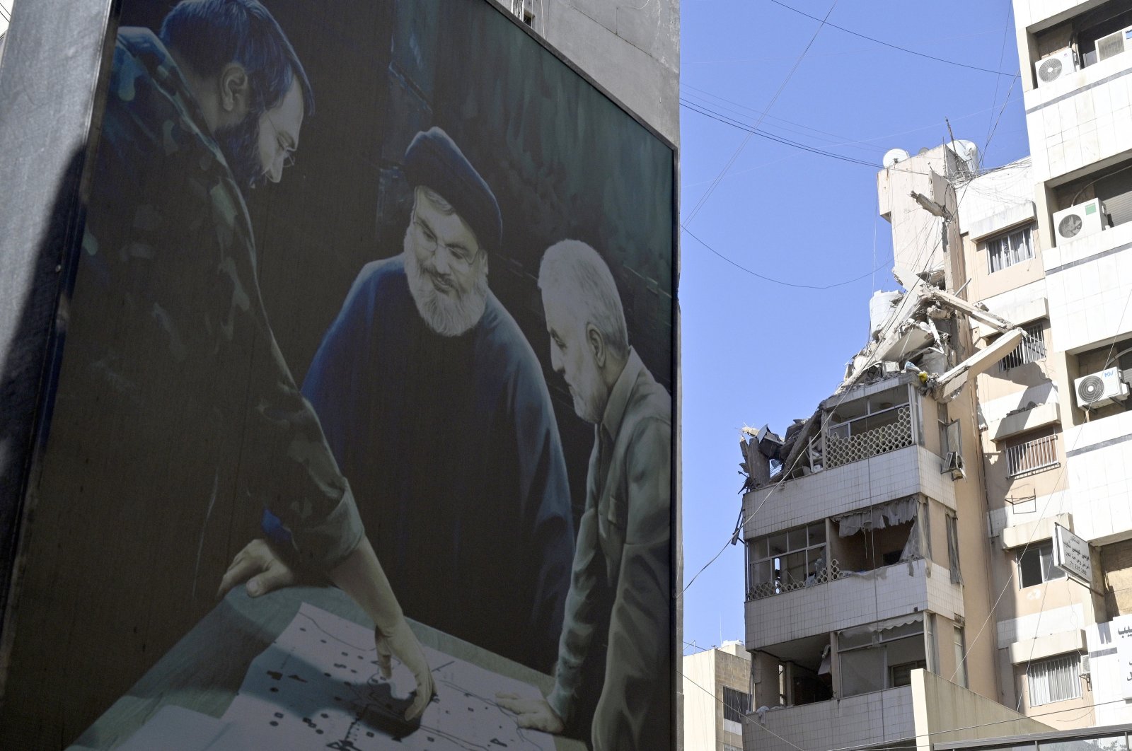 A billboard depicting late Hezbollah senior member Imad Mughniyeh (L), Hezbollah leader Hassan Nasrallah (C), and late Iranian Maj. Gen. Qassem Soleimani (R), next to a damaged building at the site of an Israeli strike the previous day in Beirut, Lebanon, July 31, 2024. (EPA Photo)