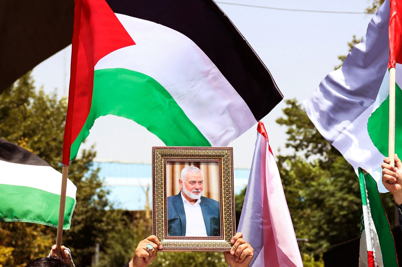 People hold up the Palestinian flag and a portrait of assassinated Hamas chief Ismail Haniyeh Hamas during a rally at Tehran University, in the Iranian capital Tehran, Iran, July 31, 2024. (AFP Photo)