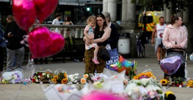 A woman holding her child looks at the floral tributes following a vigil for the victims of a knife attack in Southport, Britain, July 30, 2024. (Reuters Photo)