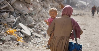 A Palestinian woman carries a child as she makes her way to return to neighborhoods in the eastern side of Khan Younis after Israeli forces pulled out from the area, Khan Younis, Gaza Strip, Palestine, July 30, 2024. (Reuters Photo)