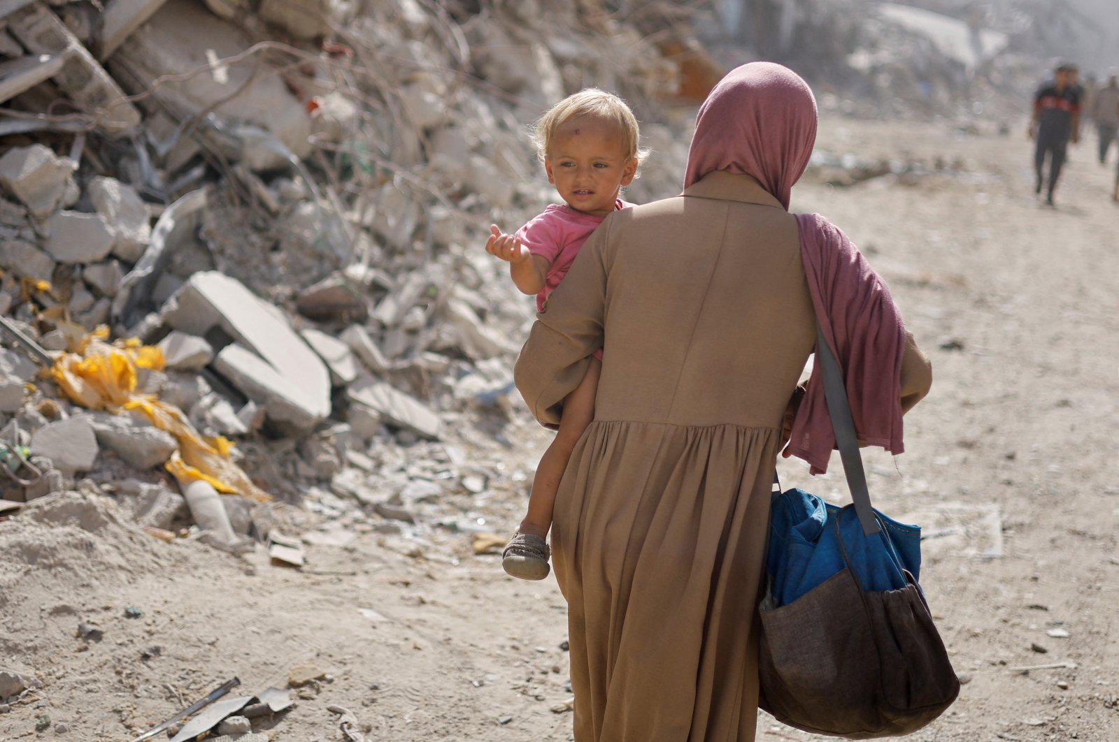 A Palestinian woman carries a child as she makes her way to return to neighborhoods in the eastern side of Khan Younis after Israeli forces pulled out from the area, Khan Younis, Gaza Strip, Palestine, July 30, 2024. (Reuters Photo)