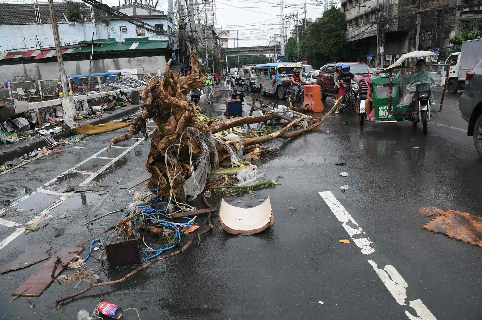 Motorists drive past a tree trunk washed along a street at the height of flooding amid heavy rains brought about by Typhoon Gaemi, Manila, Philippines, July 25, 2024. (AFP Photo)