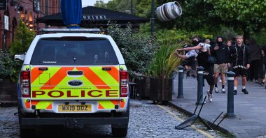 A person throws a beer keg at a police car in Bristol, southern England, Aug. 3, 2024. (AFP Photo)