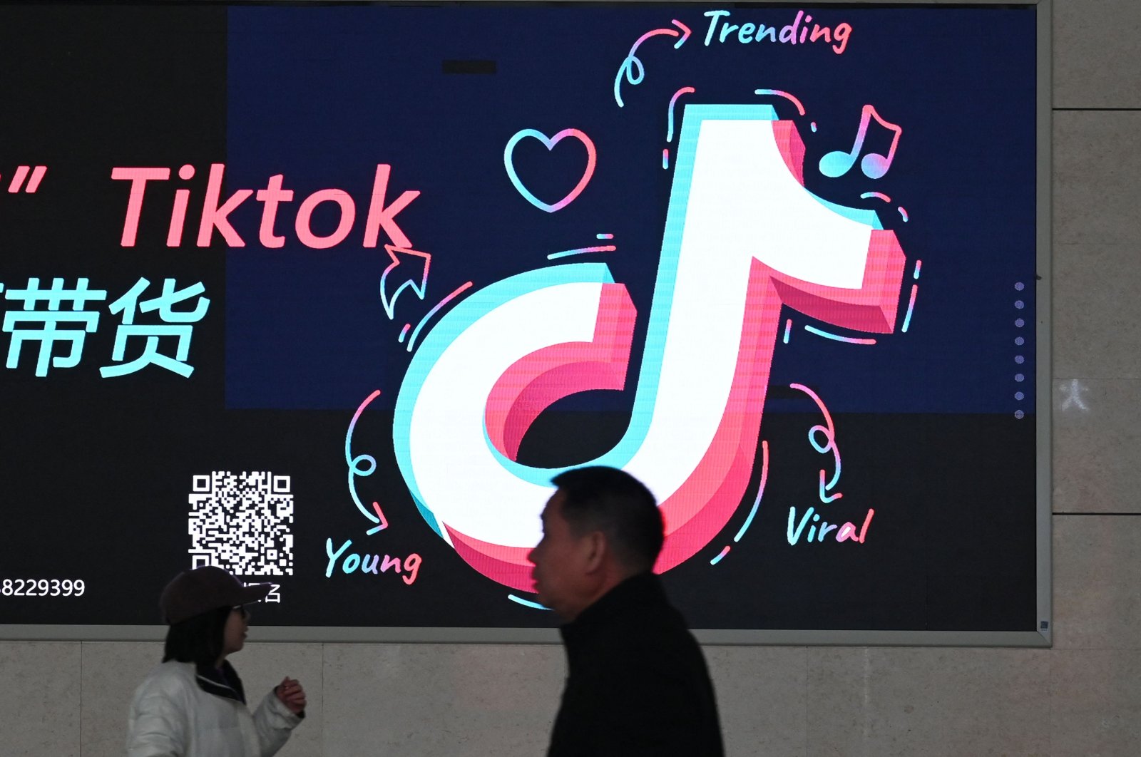 People walk past an advertisement featuring the TikTok logo at a train station in Zhengzhou, in China’s central Henan province, Jan. 21, 2024. (AFP Photo)