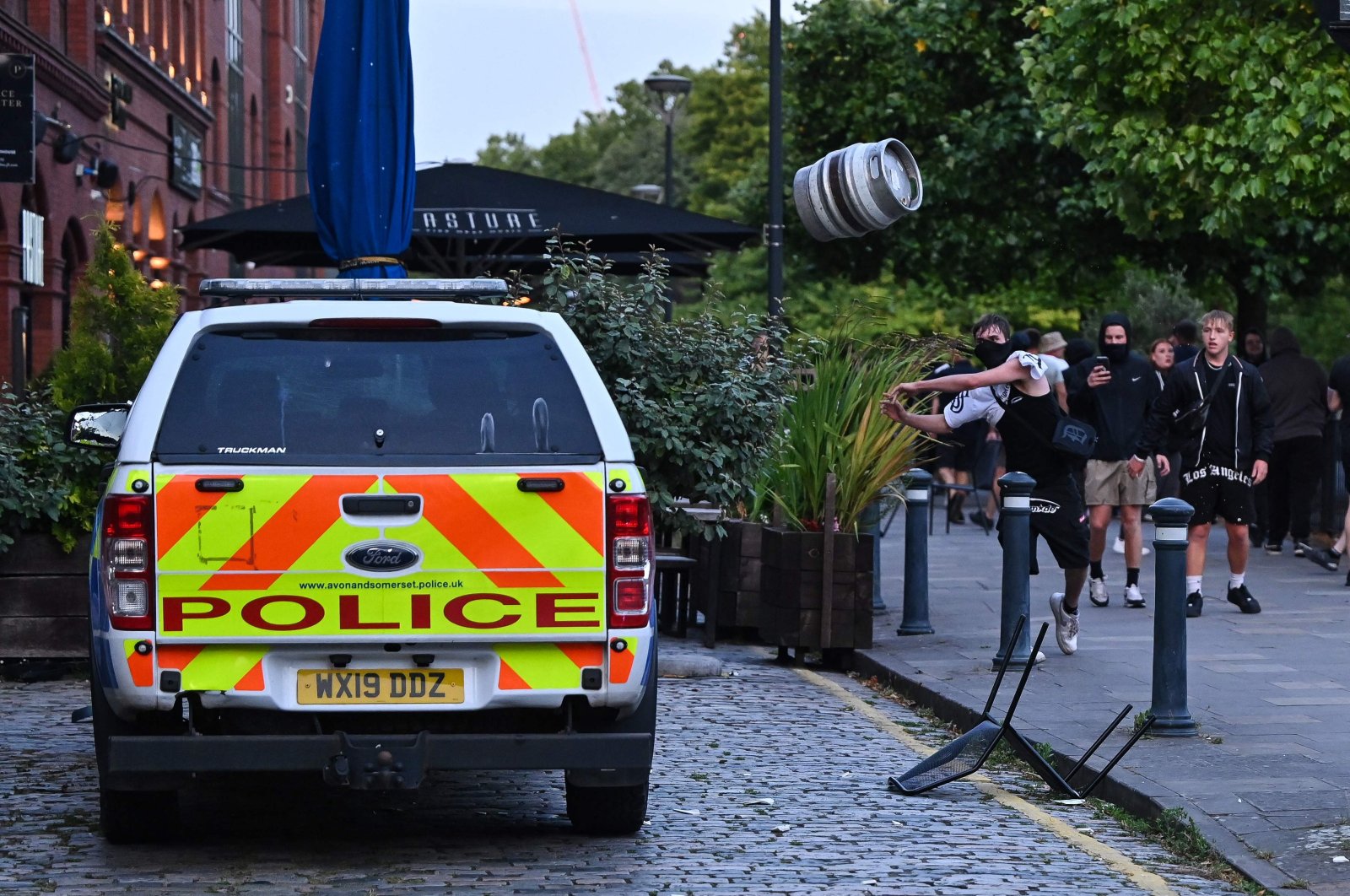 A person throws a beer keg at a police car in Bristol, southern England, Aug. 3, 2024. (AFP Photo)