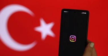 A woman holds a phone showing the Instagram logo, Istanbul, Türkiye, Aug. 3, 2024. (EPA Photo)