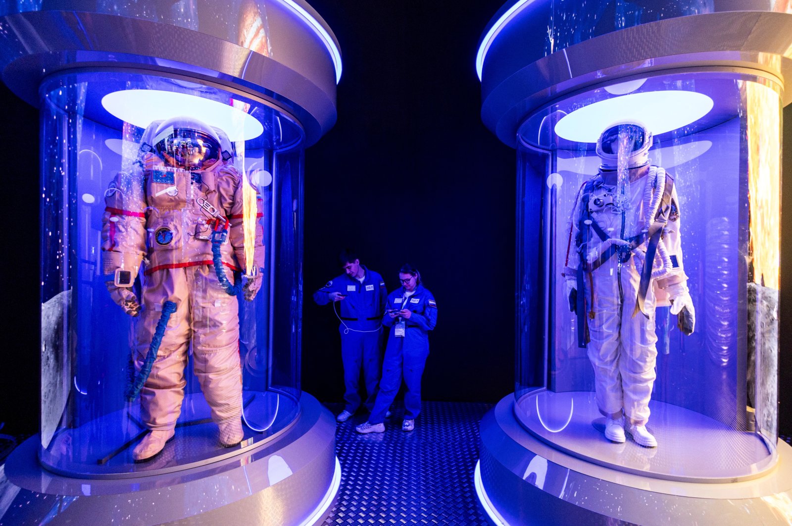 People use their mobile phones next to showcases with space suites during the forum of innovations Moscow-2030, Moscow, Russia, Aug. 1, 2024. (Reuters Photo)