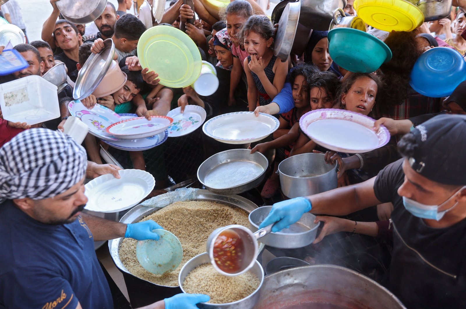 Displaced Palestinians wait to receive food at a food distribution point, set up by young men from the Madhoun family in Beit Lahia, in the northern Gaza Strip, July 18, 2024. (AFP File Photo)