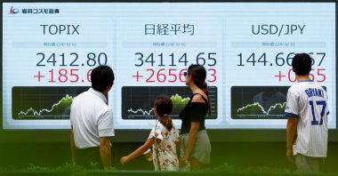 Passersby look at an electronic board displaying Topix, Japan&#039;s Nikkei share averages, and the Japanese yen exchange rate against the U.S. dollar outside a brokerage, Tokyo, Japan, Aug. 6, 2024. (Reuters Photo)