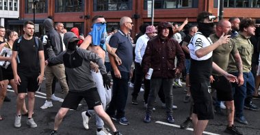 A masked far-right extremist throws a can of beer toward riot police in Bristol, southern England, Aug. 3, 2024. (AFP Photo)
