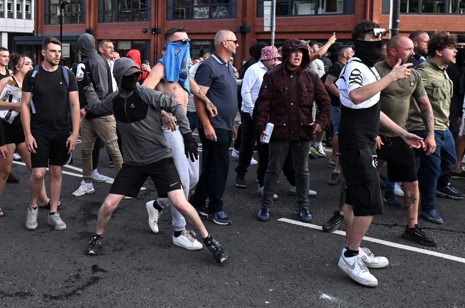 A masked far-right extremist throws a can of beer toward riot police in Bristol, southern England, Aug. 3, 2024. (AFP Photo)