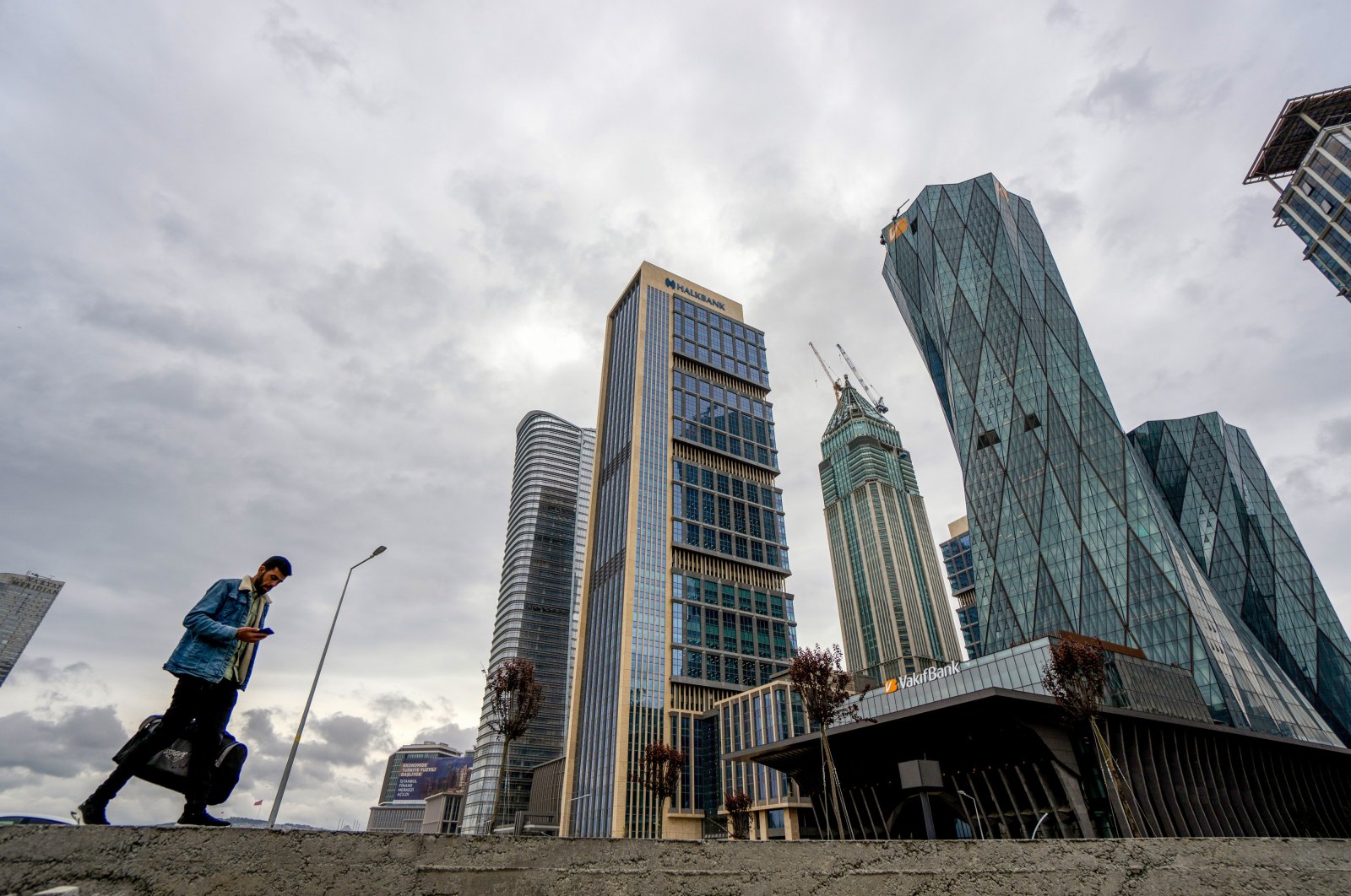 A pedestrian passes skyscraper office buildings close to the Istanbul Financial Center (IFC), Istanbul, Türkiye, May 9, 2023. (Getty Images Photo)