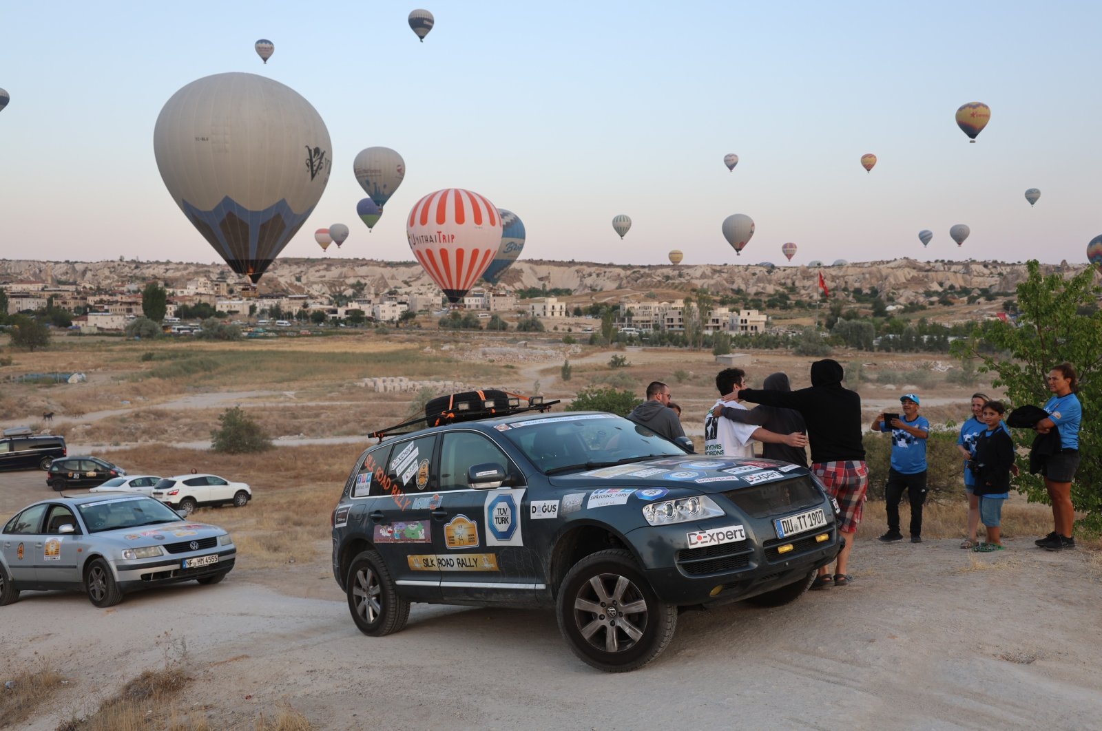 A rally car waits with hot air balloons in the background, Cappadocia, Türkiye, Aug. 6, 2024. (IHA Photo)