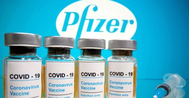 Vials with a sticker reading, "COVID-19 / Coronavirus vaccine / Injection only" and a medical syringe are seen in front of a displayed Pfizer logo in this illustration taken on Oct. 31, 2020. (Reuters Photo)