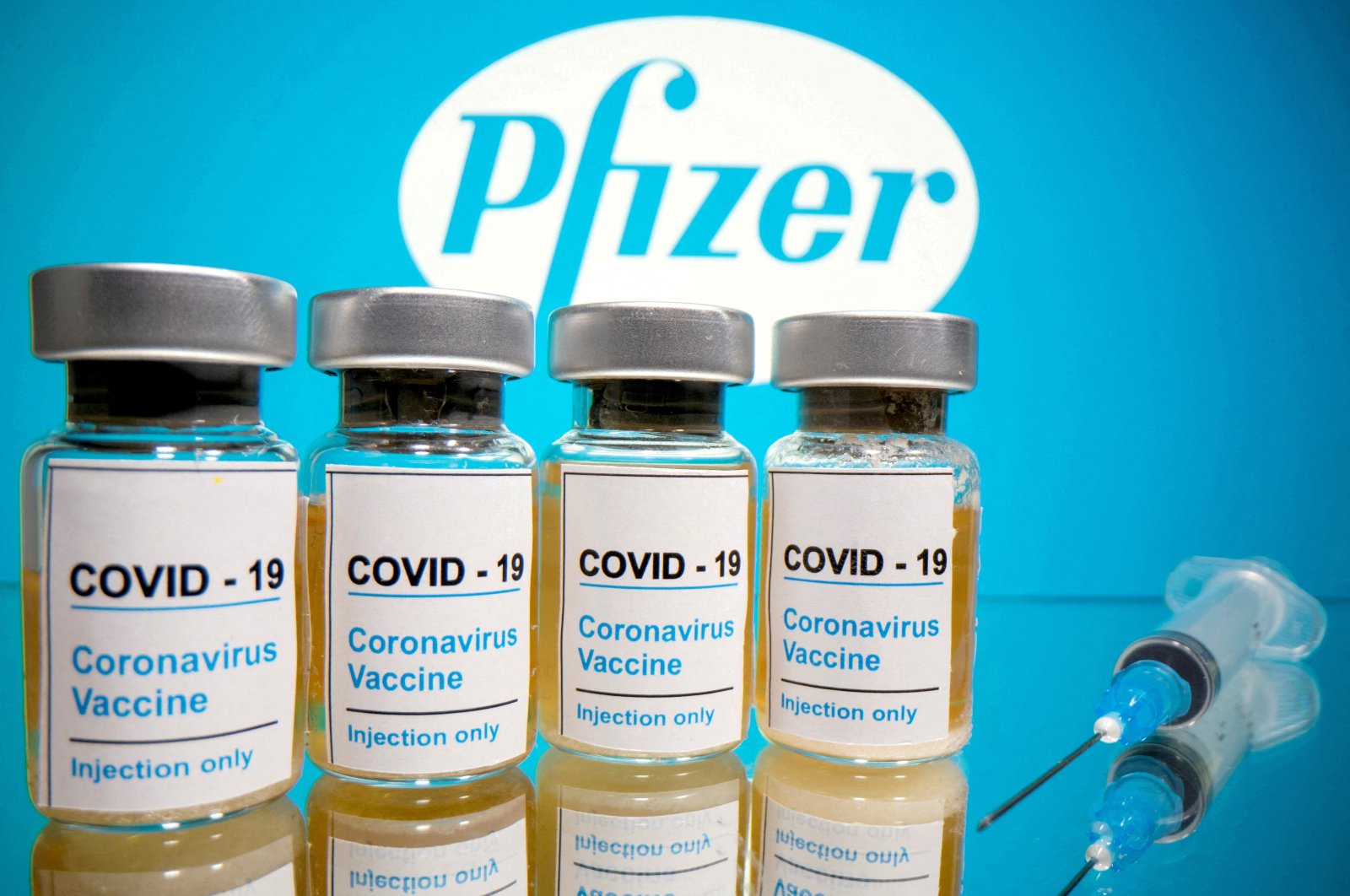 Vials with a sticker reading, &quot;COVID-19 / Coronavirus vaccine / Injection only&quot; and a medical syringe are seen in front of a displayed Pfizer logo in this illustration taken on Oct. 31, 2020. (Reuters Photo)