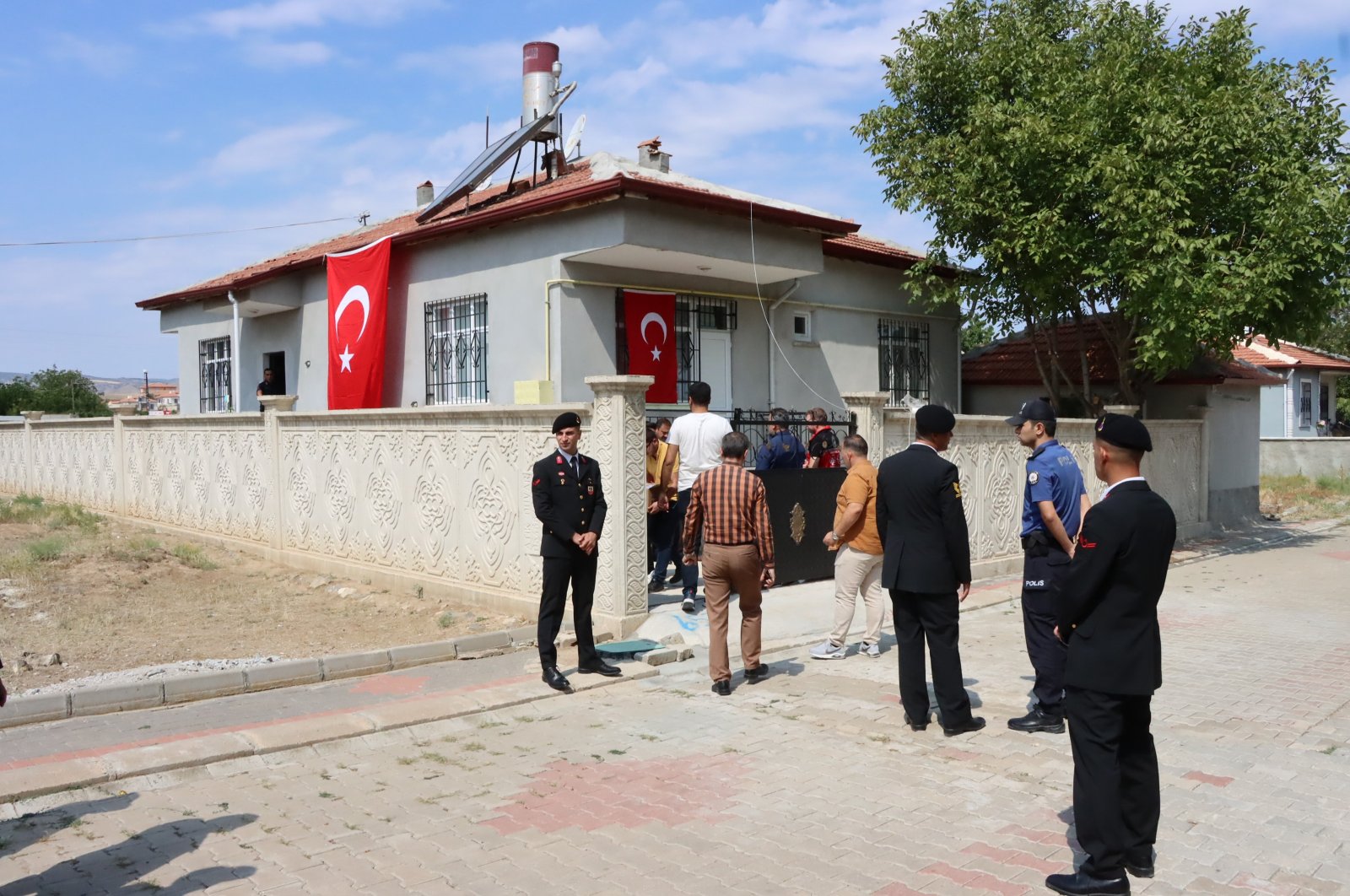 Officers stand guard as residents offer condolences outside Habip Murat Alp&#039;s family home after Alp was killed in by PKK harassment fire, central Kırşehir province, Türkiye, July 7, 2024. (AA Photo)