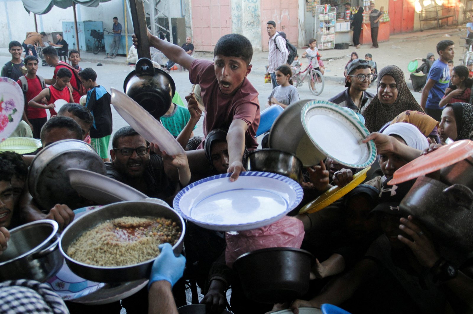  Palestinian children gather to receive food cooked by a charity kitchen, amid food scarcity, in the northern Gaza Strip, July 18, 2024. (Reuters File Photo)