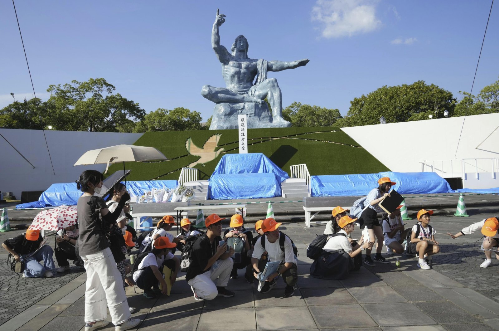 Visitors to the Peace Park crouch as an earthquake alert was issued in Nagasaki, western Japan, Aug. 8, 2024. (AP Photo)