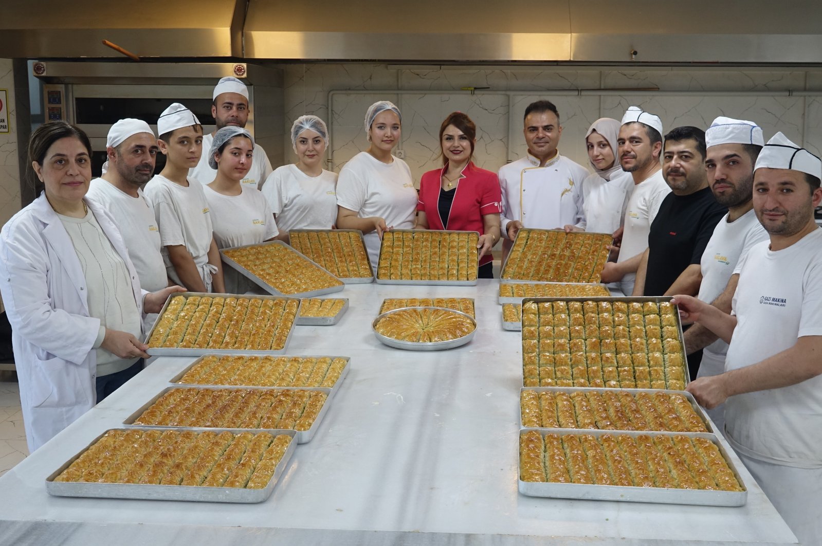 Students pose with chefs at the Gaziantep Baklava Academy, Gaziantep, Türkiye, Aug. 7, 2024. (IHA Photo)