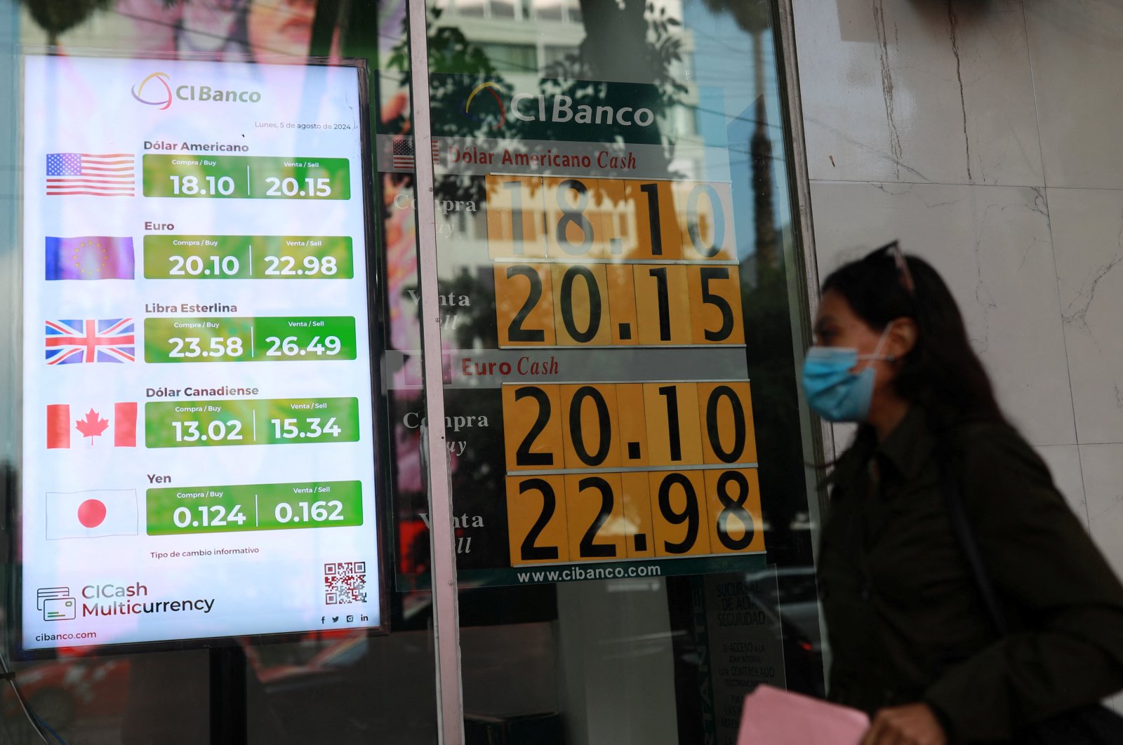 A woman walks past boards showing the exchange rates of the Mexican peso against the U.S. dollar and the euro at a bank, Mexico City, Mexico, Aug. 5, 2024. (Reuters Photo)
