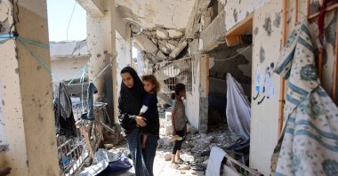  A Palestinian woman carrying a child checks the damage at the al-Zahra school used as a refuge by displaced Palestinians, after it was hit by an Israeli strike in the Shujaiya neighborhood of Gaza City, Aug. 8, 2024. (AFP Photo)