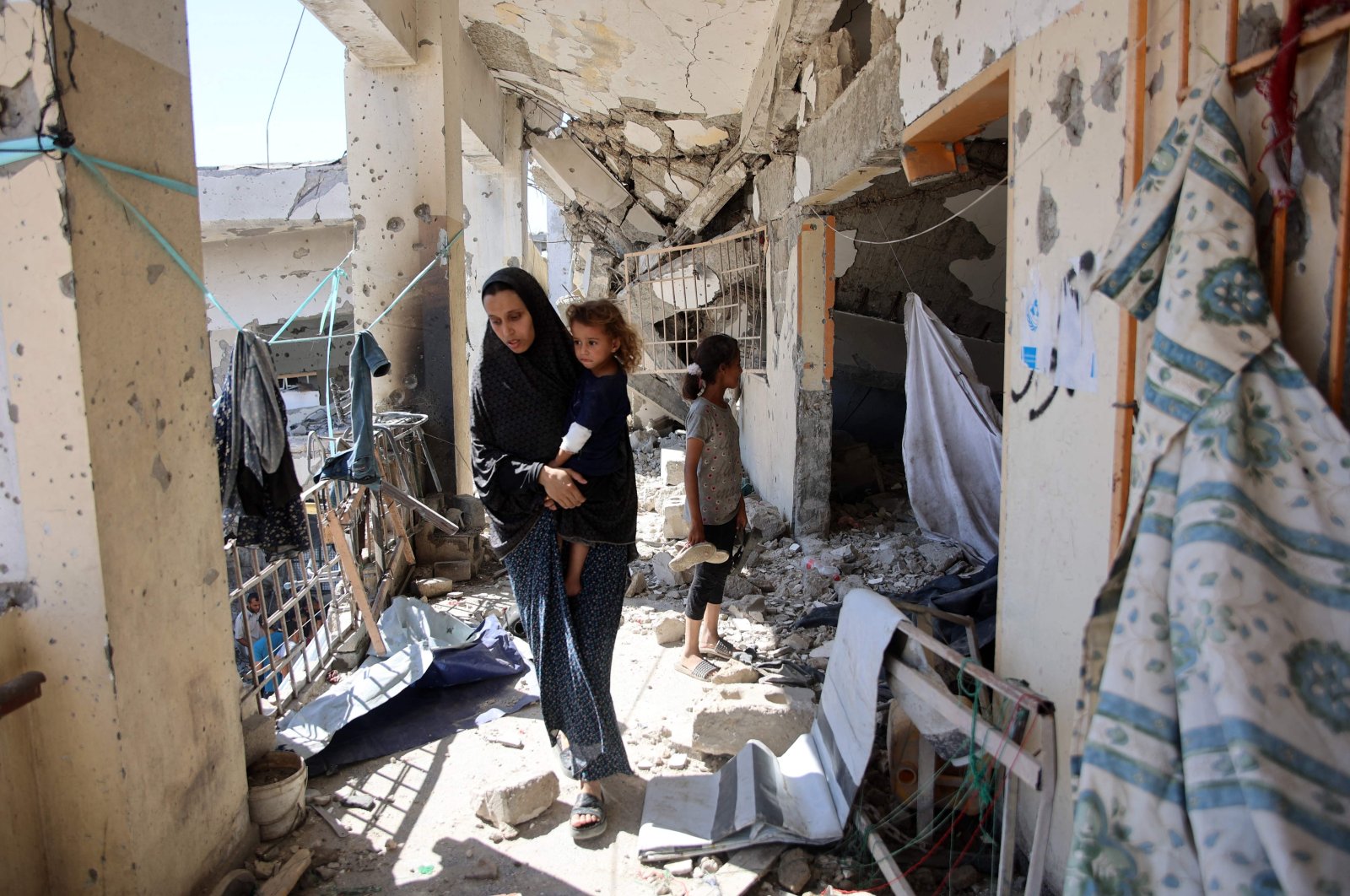  A Palestinian woman carrying a child checks the damage at the al-Zahra school used as a refuge by displaced Palestinians, after it was hit by an Israeli strike in the Shujaiya neighborhood of Gaza City, Aug. 8, 2024. (AFP Photo)