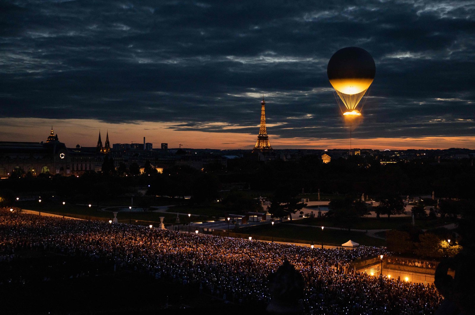 A crowd points their phones toward the cauldron of the Paris 2024 Olympic and Paralympic Games with the Eiffel Tower in the background, Paris, France, Aug. 8, 2024. (AFP Photo)