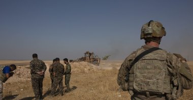  U.S. special forces soldier and YPG terrorists watch a bulldozer dismantle a fortification on the border with Türkiye near Tal Abyad, Syria. (AP File Photo)