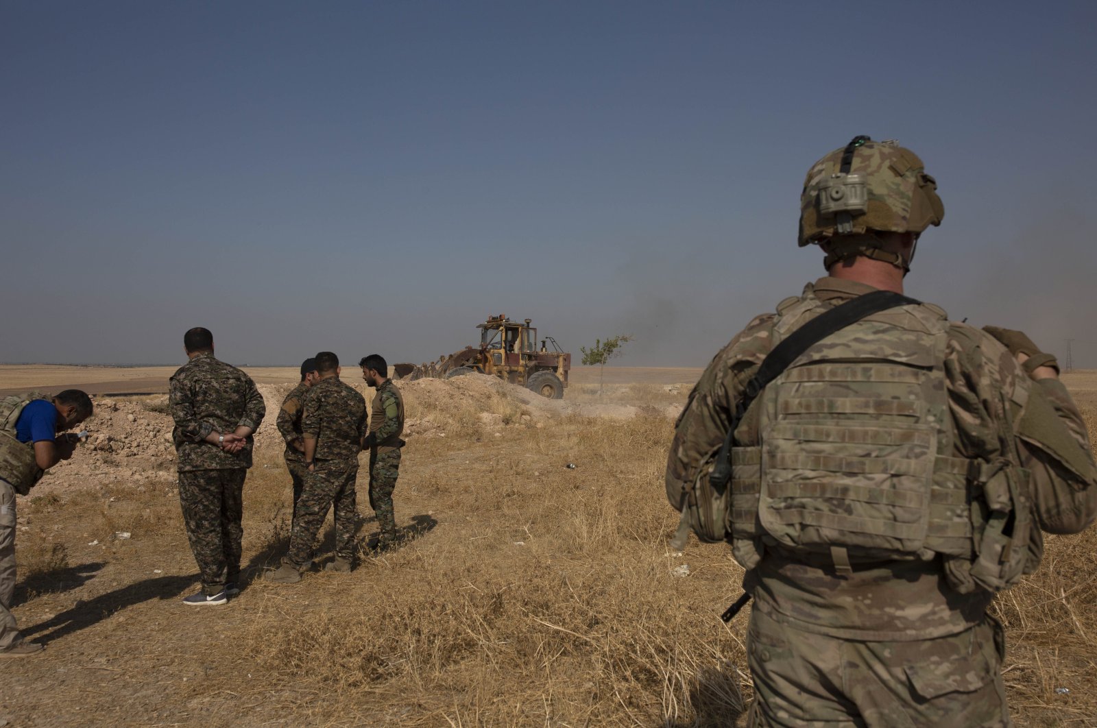  U.S. special forces soldier and YPG terrorists watch a bulldozer dismantle a fortification on the border with Türkiye near Tal Abyad, Syria. (AP File Photo)