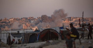  Smoke rises following an Israeli air strike as internally displaced Palestinians sit next to their tents in Khan Younis camp, southern Gaza Strip, Aug. 13, 2024. (EPA Photo)