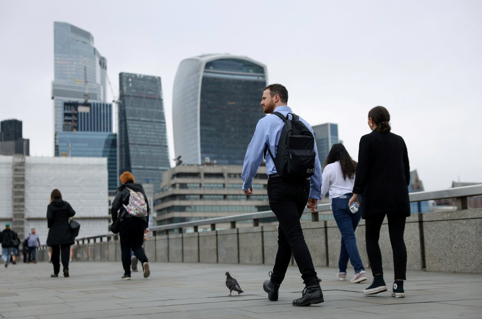 Commuters cross London Bridge in view of the City of London skyline, Britain, July 25, 2024. (Reuters Photo)