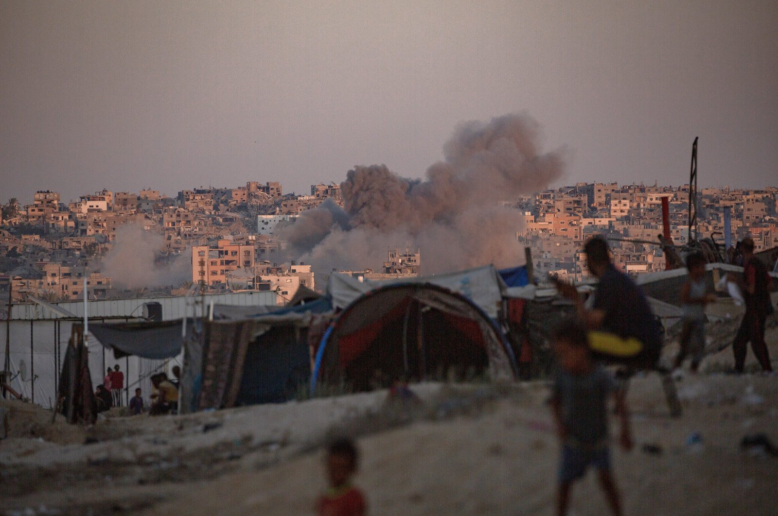  Smoke rises following an Israeli air strike as internally displaced Palestinians sit next to their tents in Khan Younis camp, southern Gaza Strip, Aug. 13, 2024. (EPA Photo)