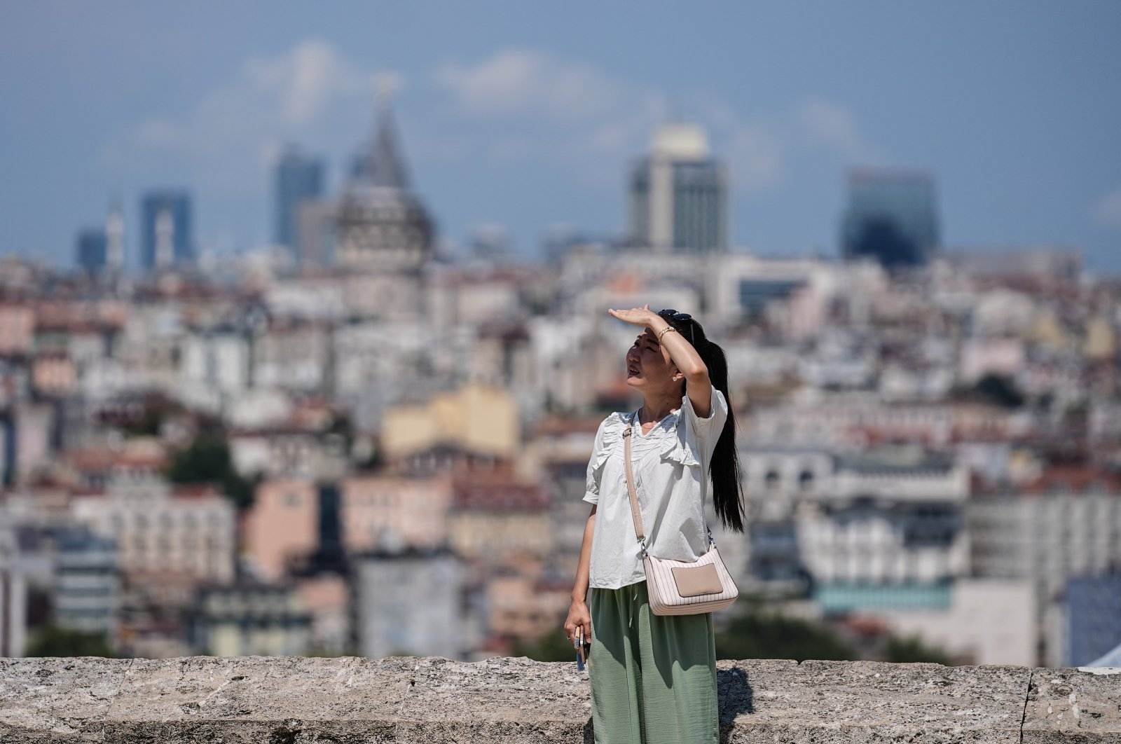 A tourist is photographed with a backdrop of the landmark Galata Tower, Istanbul, Türkiye, July 23, 2024. (AA Photo)