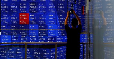 A man takes a photo next to an electronic stock quotation board inside a building in Tokyo, Japan Aug. 2, 2024. (Reuters Photo)