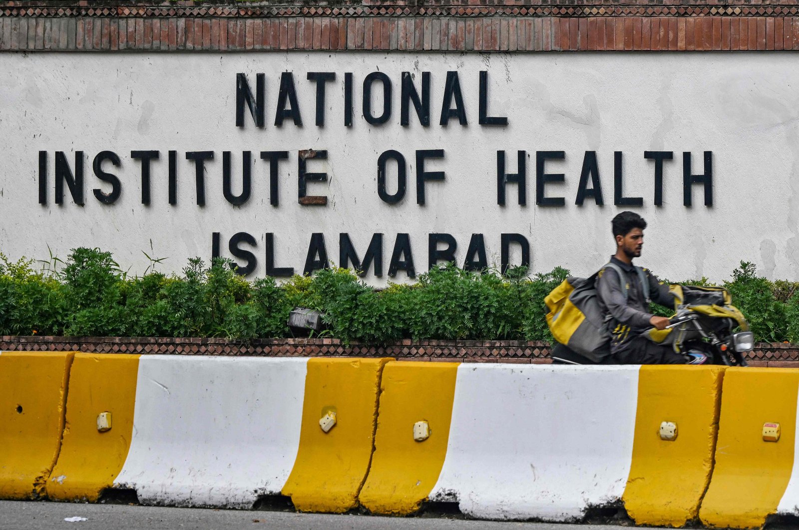 A delivery boy rides past the building of the National Institute of Health (NIH), a Pakistani research institute mainly responsible for biomedical and health-related research, Islamabad, Pakistan, Aug. 16, 2024. (AFP Photo)