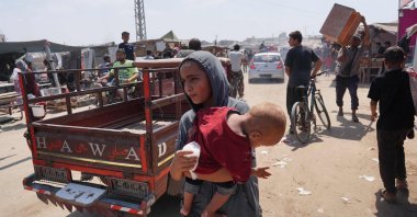 A Palestinian girl carries a toddler as she flees with others from a makeshift camp upon arrival of Israeli tanks, southern Gaza Strip, Palestine, Aug. 18, 2024. (AFP Photo)