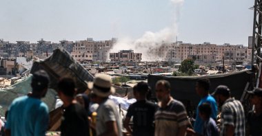 Displaced Palestinians watch from a makeshift camp as shells fired from Israeli tanks hit an area in Khan Younis, southern Gaza Strip, Palestine, Aug. 18, 2024. (AFP Photo)