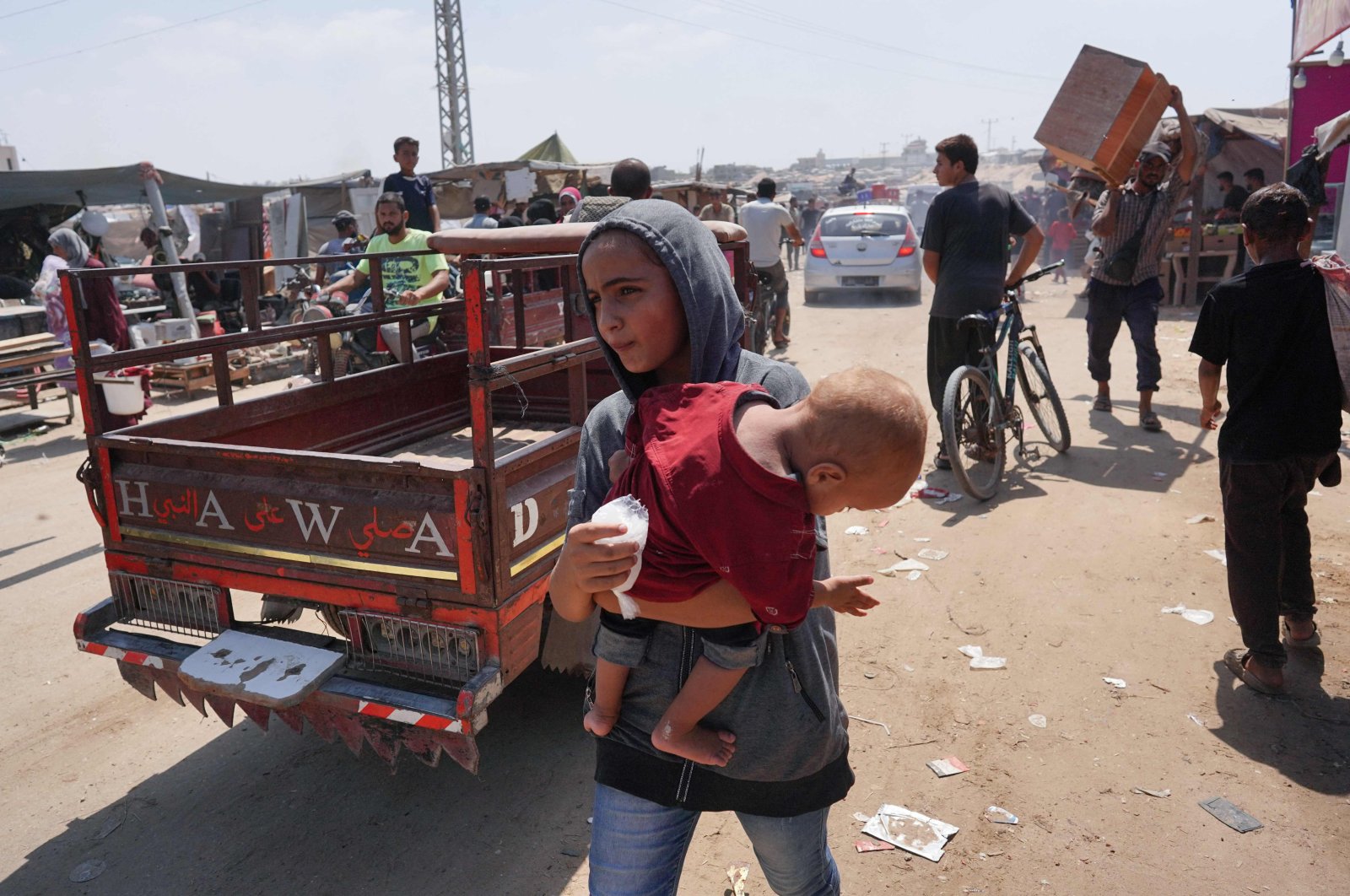 A Palestinian girl carries a toddler as she flees with others from a makeshift camp upon arrival of Israeli tanks, southern Gaza Strip, Palestine, Aug. 18, 2024. (AFP Photo)