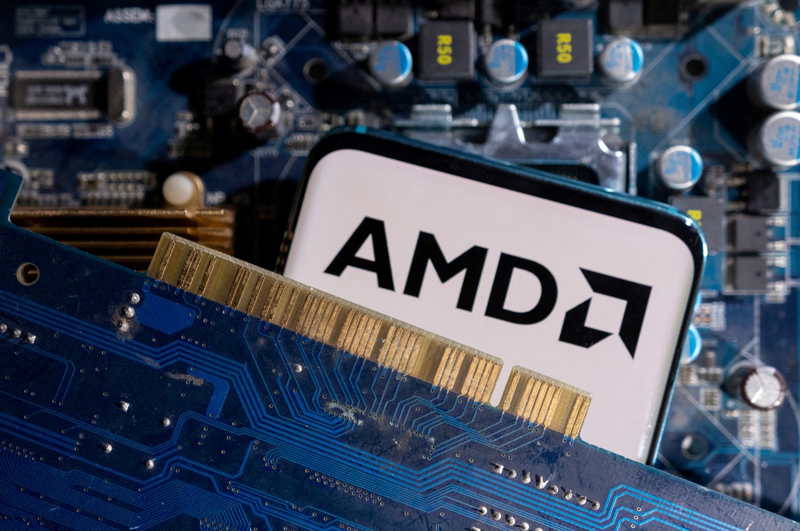 A smartphone with an AMD logo is placed on a computer motherboard in this illustration taken March 6, 2023. (Reuters Photo)