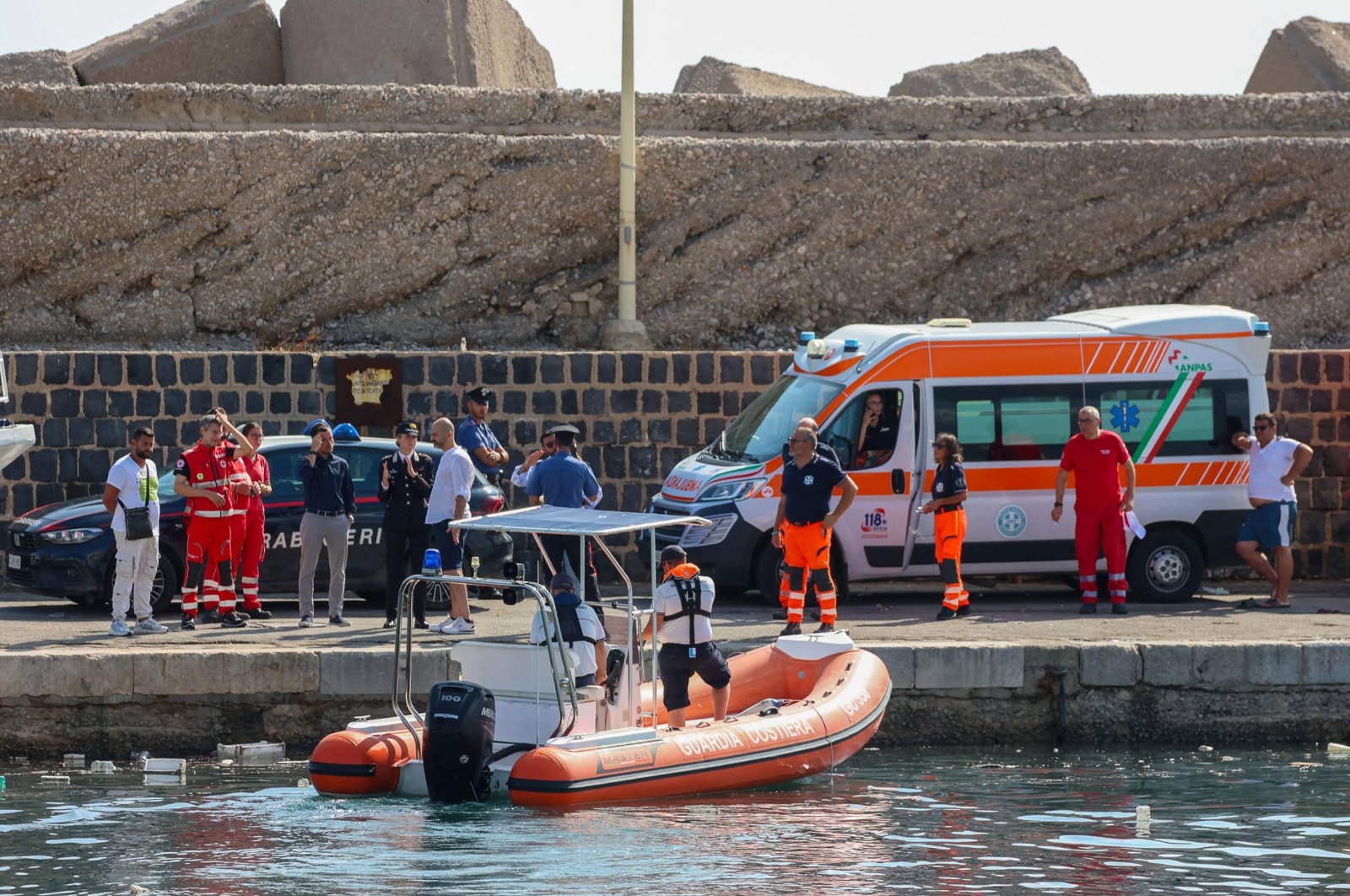 Italian Carabinieri and health workers wait on the quay as the coast guard searches for six missing people after a sailboat sank off Porticello, Sicily, Aug. 19, 2024. (AFP Photo)