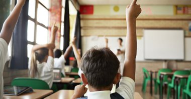 Students raise their hands to speak during class. (Getty Images)