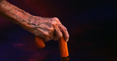 An elderly person holds a walking stick. (Getty Images)