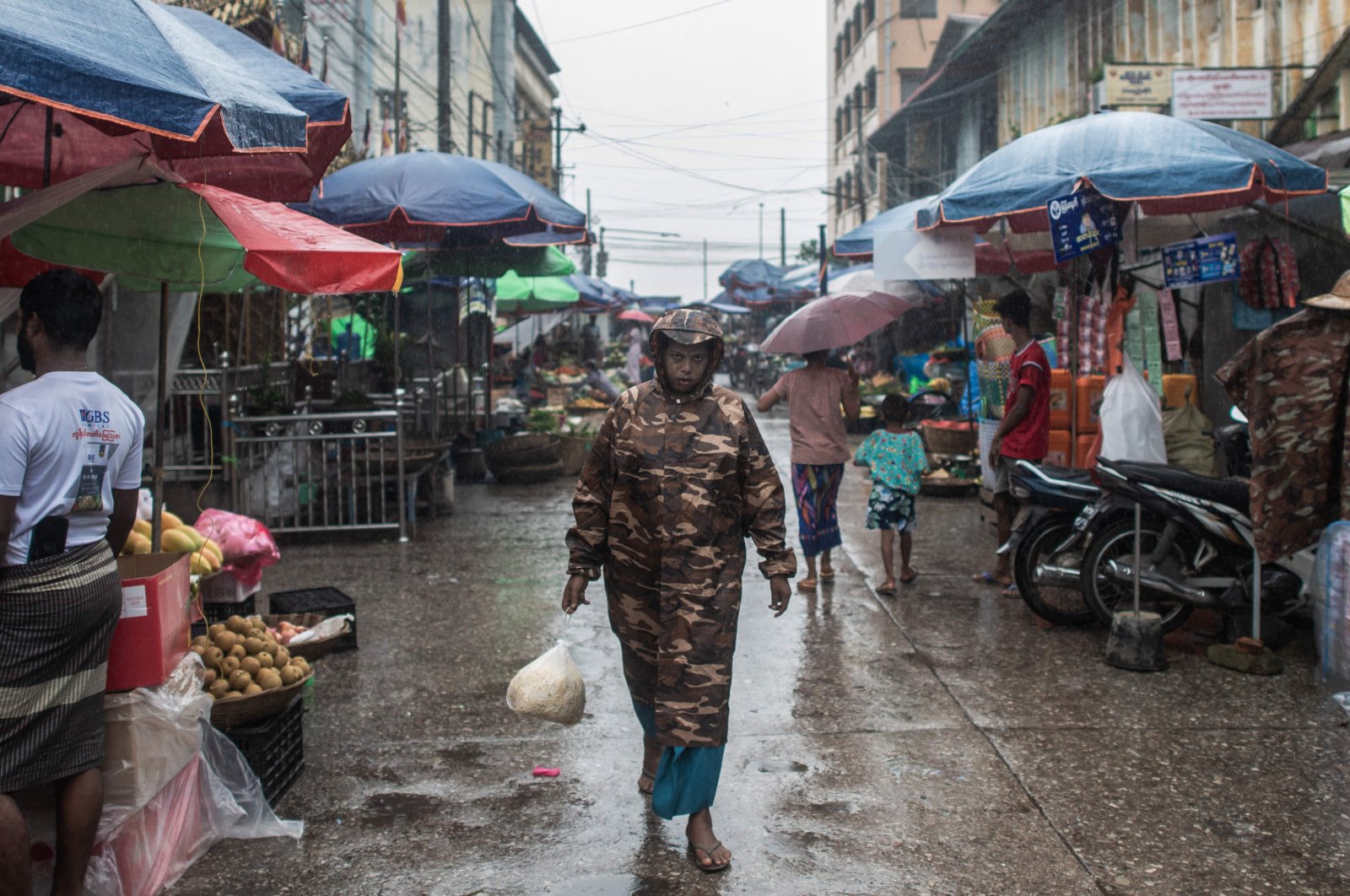 A woman walks down a street market as rain falls in Mawlamyaing in Myanmar’s Mon state, July 16, 2024. (AFP Photo)