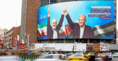 Vehicles drive past a huge billboard depicting Iranian President Masoud Pezeshkian (R) and slain Palestinian Hamas leader Ismail Haniyeh at Tehran&#039;s Valiasr square, Tehran, Iran, Aug. 12, 2024. (AFP Photo)
