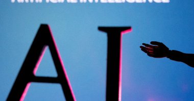 Artificial Intelligence (AI) letters and robot hand miniature are seen in this illustration taken on June 23, 2023. (Reuters Photo)