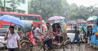 People shelter under umbrellas during rainfall as they walk and ride along a street, Dhaka, Bangladesh, Aug. 21, 2024. (EPA Photo)